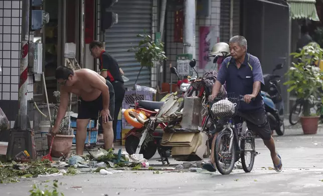 People clear debris in the aftermath of Typhoon Krathon in Kaohsiung, southern Taiwan, Friday, Oct. 4, 2024. (AP Photo/Chiang Ying-ying)