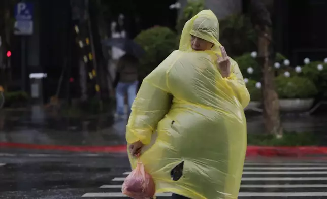 A woman struggles with wind and rain generated by Typhoon Kong-rey in Taipei, Taiwan, Thursday, Oct. 31, 2024. (AP Photo/Chiang Ying-ying)