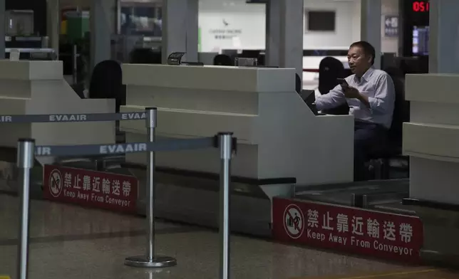 An airline staffer works at the counter at a closed airport due to approaching Typhoon Krathon, in Kaohsiung, southern Taiwan, Wednesday, Oct. 2, 2024. (AP Photo/Chiang Ying-ying)