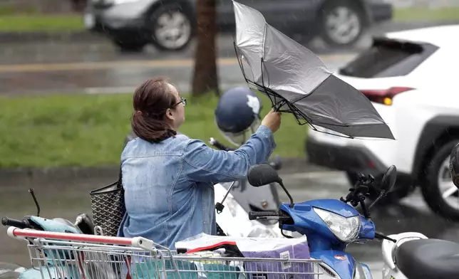 A woman struggles with winds generated by Typhoon Krathon in Kaohsiung, Southern Taiwan, Wednesday, Oct. 2, 2024. (AP Photo/Chiang Ying-ying)