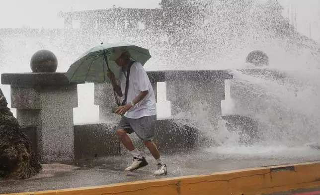 A man runs away from waves when he was walking along the shore in Kaohsiung, Southern Taiwan, Wednesday, Oct. 2, 2024, as Typhoon Krathon is expected to hit the area. (AP Photo/Chiang Ying-ying)