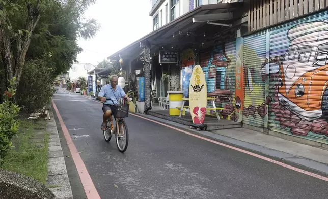 A man rides a bicycle on Surf Street as Typhoon Krathon approaches to Taiwan in Yilan County, eastern coast of Taiwan, Tuesday, Oct. 1, 2024. (AP Photo/Chiang Ying-ying)