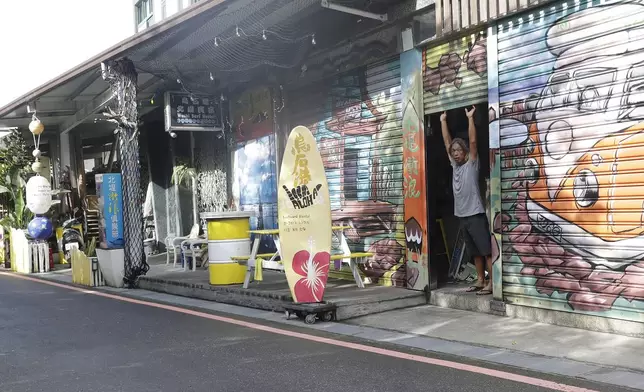 A man opens the door of his shop as Typhoon Krathon approaches to Taiwan in Yilan County, eastern coast of Taiwan, Tuesday, Oct. 1, 2024. (AP Photo/Chiang Ying-ying)