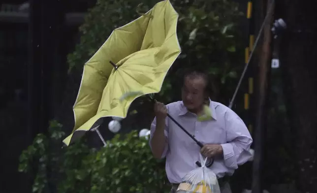 A man struggles with his umbrella against gusts of wind generated by Typhoon Kong-rey in Taipei, Taiwan, Thursday, Oct. 31, 2024. (AP Photo/Chiang Ying-ying)