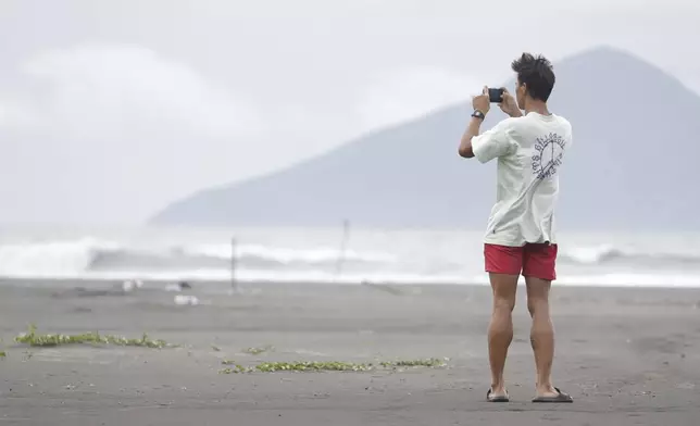 A man takes a photo on a beach as Typhoon Krathon approaches to Taiwan in Yilan County, eastern coast of Taiwan, Tuesday, Oct. 1, 2024. (AP Photo/Chiang Ying-ying)