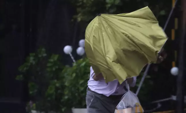 A man struggles with his umbrella against gusts of wind generated by Typhoon Kong-rey in Taipei, Taiwan, Thursday, Oct. 31, 2024. (AP Photo/Chiang Ying-ying)