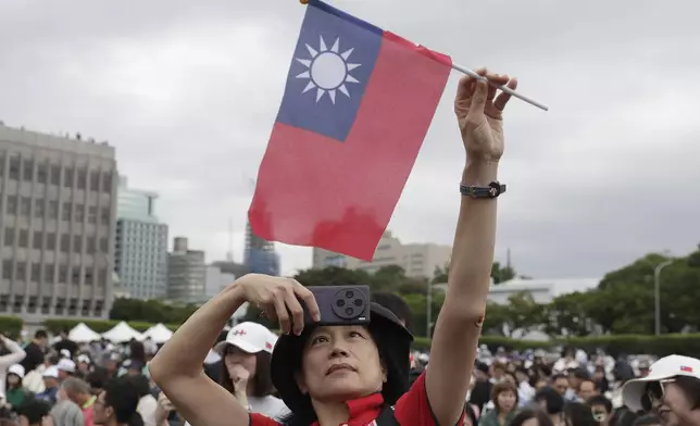 A person poses with Taiwan's national flag for a photo during National Day celebrations in front of the Presidential Building in Taipei, Taiwan, Thursday, Oct. 10, 2024. (AP Photo/Chiang Ying-ying)