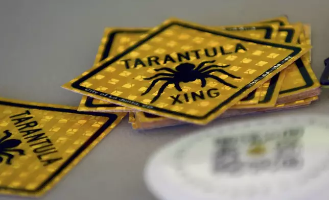 Tarantula crossing stickers are piled on a table at the Tarantula Festival in La Junta, Colo., on Saturday, Sept. 28, 2024. (AP Photo/Thomas Peipert)