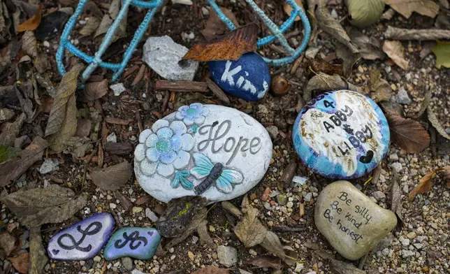 Decorated stones bearing the names of Abigail Williams and Liberty German, who were killed in February 2017, are placed at a memorial along the Monon High Bridge Trail in Delphi, Ind., Tuesday, Oct. 1, 2024. (AP Photo/Michael Conroy)