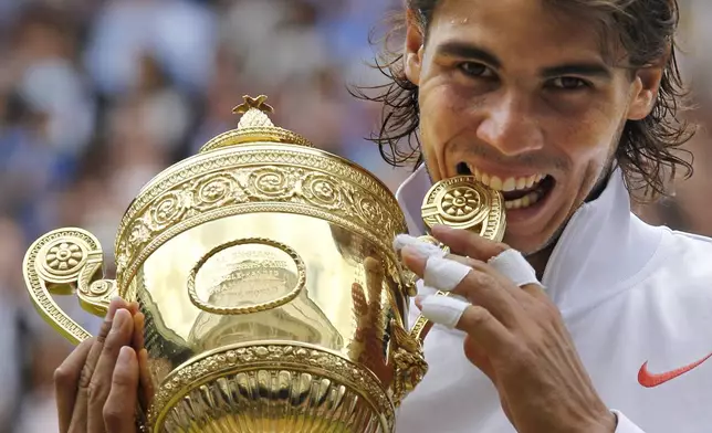 FILE - Rafael Nadal bites the trophy, after defeating Tomas Berdych in the men's singles final on the Centre Court at the All England Lawn Tennis Championships at Wimbledon, Sunday, July 4, 2010, as he has announced he will retire from tennis at age 38 following the Davis Cup finals in November. (AP Photo/Anja Niedringhaus, File)