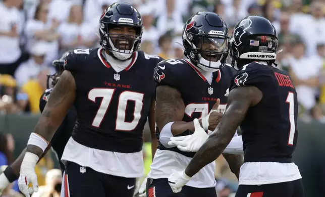 Teammates Houston Texans center Juice Scruggs (70) and wide receiver Stefon Diggs (1) celebrate with running back Joe Mixon (28) after he scored a touchdown during the first half of an NFL football game against the Green Bay Packers, Sunday, Oct. 20, 2024, in Green Bay, Wis. (AP Photo/Matt Ludtke)