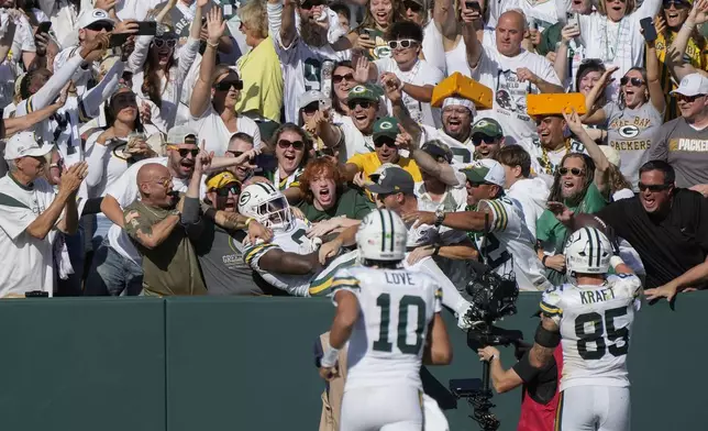 Green Bay Packers running back Josh Jacobs (8) jumps in the crowd after catching a touchdown pass during the second half of an NFL football game against the Houston Texans, Sunday, Oct. 20, 2024, in Green Bay, Wis. (AP Photo/Morry Gash)