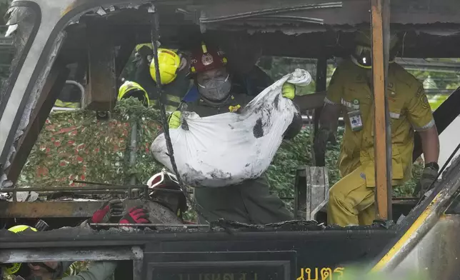 Rescuers carry the body of a victim of a bus that caught fire, carrying young students with their teachers, in suburban Bangkok, Tuesday, Oct. 1, 2024. (AP Photo/Sakchai Lalit)
