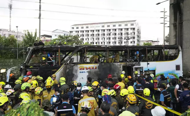 Rescuer inspect a bus which caught fire as it was carrying young students with their teachers, in suburban Bangkok, Tuesday, Oct. 1, 2024. (AP Photo/Sakchai Lalit)