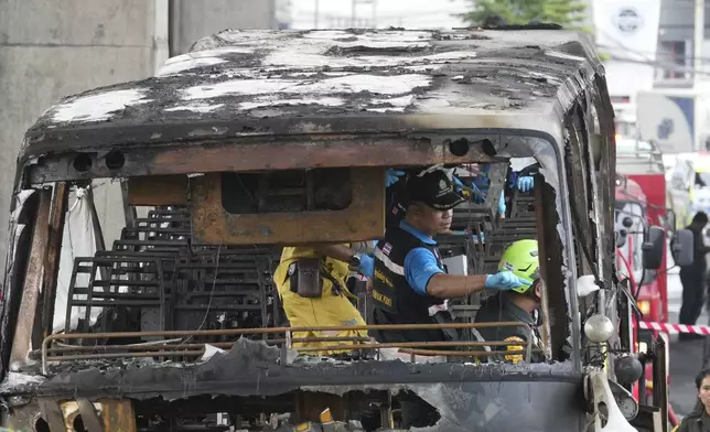 Officers of a police forensics team inspect a bus that caught fire, carrying young students with their teachers, in suburban Bangkok, Tuesday, Oct. 1, 2024. (AP Photo/Sakchai Lalit)