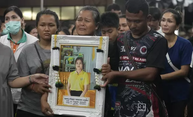 Victims' relatives carry portraits of the victims of a bus fire in a procession at Wat Khao Phraya Sangkharam School Lan Sak, Uthai Thani province, Thailand, Thursday, Oct. 3, 2024. (AP Photo/Sakchai Lalit)