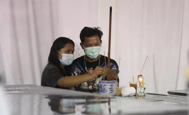 Relatives of the bus fire victims pray at their coffins at Wat Khao Phraya Sangkharam School Lan Sak, Uthai Thani province, Thailand, Wednesday, Oct. 2, 2024. (AP Photo/Sakchai Lalit)