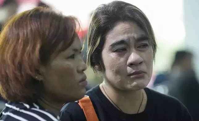 Relatives mourn nears the coffins of victims of school bus fire at Wat Khao Phraya Sangkharam School, Lan Sak, Uthai Thani province, Thailand, Thursday, Oct. 3, 2024. (AP Photo/Sakchai Lalit)