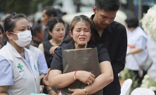 A family member mourns during the cremation ceremony for victims of a school bus fire, at Wat Khao Phraya Sangkharam School, Lan Sak, Uthai Thani province, Thailand, Tuesday, Oct. 8, 2024. (AP Photo/Chatkla Samnaingjam)