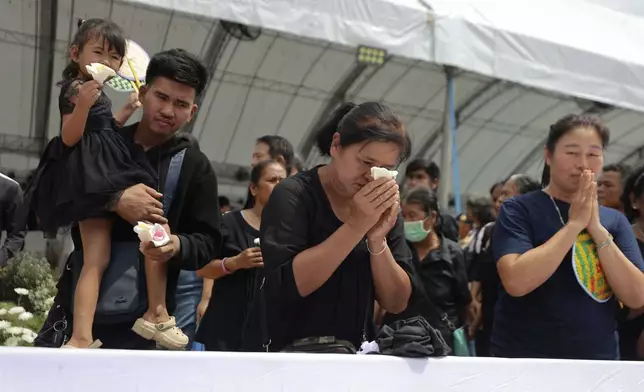 People offer their final respects at the cremation for victims of a school bus fire, at Wat Khao Phraya Sangkharam School, Lan Sak, Uthai Thani province, Thailand, Tuesday, Oct. 8, 2024. (AP Photo/Chatkla Samnaingjam)