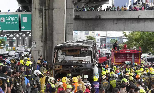 Rescuers gather at the site of a bus that caught fire, carrying young students with their teachers, in suburban Bangkok, Tuesday, Oct. 1, 2024. (AP Photo/Sakchai Lalit)