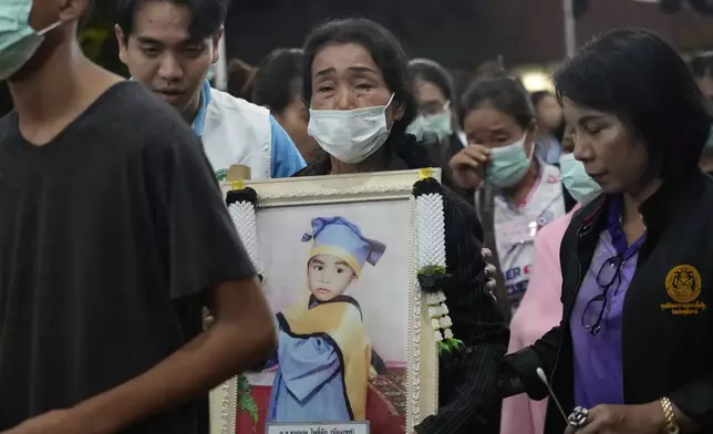 Relatives of victims in a bus fire carry portraits of the deceased in a procession at Wat Khao Phraya Sangkharam School Lan Sak , Uthai Thani province, Thailand, Thursday, Oct. 3, 2024. (AP Photo/Sakchai Lalit)