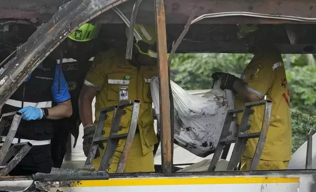 Rescuers carry the body of a victim of a bus that caught fire, carrying young students with their teachers, in suburban Bangkok, Tuesday, Oct. 1, 2024. (AP Photo/Sakchai Lalit)