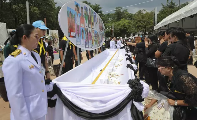 People offer their final respects at the cremation for victims of a school bus fire, at Wat Khao Phraya Sangkharam School, Lan Sak, Uthai Thani province, Thailand, Tuesday, Oct. 8, 2024. (AP Photo/Chatkla Samnaingjam)