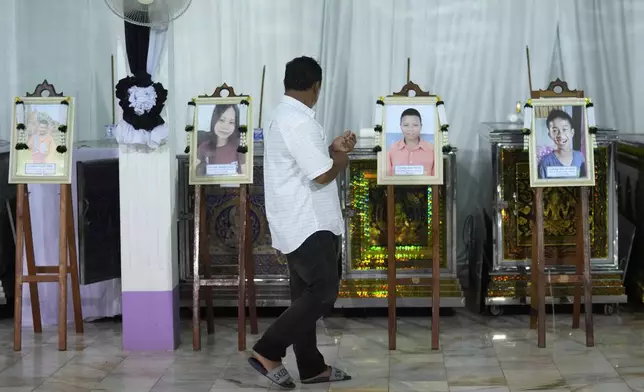 A relative of the bus fire victims walks in front of their coffins at the Wat Khao Phraya Sangkharam School Lan Sak , Uthai Thani province, Thailand, Wednesday, Oct. 2, 2024. (AP Photo/Sakchai Lalit)