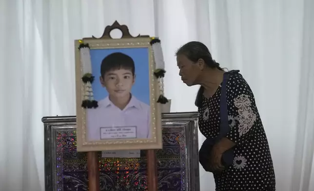 A relative looks at the coffin of a victim of school bus fire at Wat Khao Phraya Sangkharam School, Lan Sak, Uthai Thani province, Thailand, Thursday, Oct. 3, 2024. (AP Photo/Sakchai Lalit)