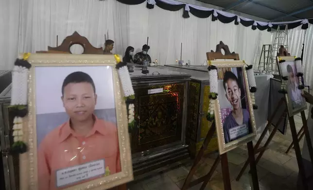 Portraits of the bus fire victims are placed in front of their coffins at the Wat Khao Phraya Sangkharam School Lan Sak, Uthai Thani province, Thailand, Wednesday, Oct. 2, 2024. (AP Photo/Sakchai Lalit)