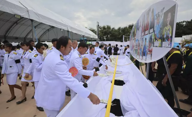 People offer their final respects at the cremation for victims of a school bus fire, at Wat Khao Phraya Sangkharam School, Lan Sak, Uthai Thani province, Thailand, Tuesday, Oct. 8, 2024. (AP Photo/Chatkla Samnaingjam)