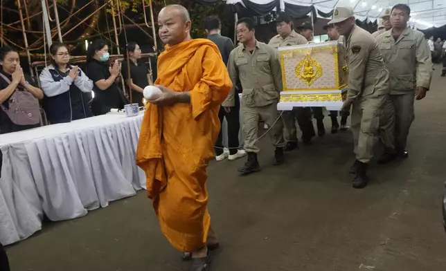 A monk leads a coffin procession containing the body of a victim of a bus fire as they arrive at Wat Khao Phraya Sangkharam School Lan Sak , Uthai Thani province, Thailand, Thursday, Oct. 3, 2024. (AP Photo/Sakchai Lalit)