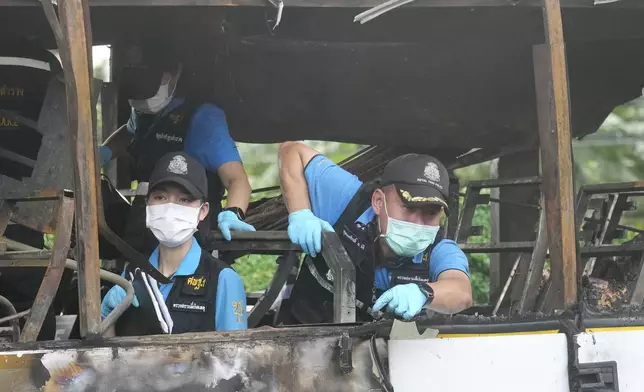 Officers of a police forensics team inspect a bus that caught fire, carrying young students with their teachers, in suburban Bangkok, Tuesday, Oct. 1, 2024. (AP Photo/Sakchai Lalit)