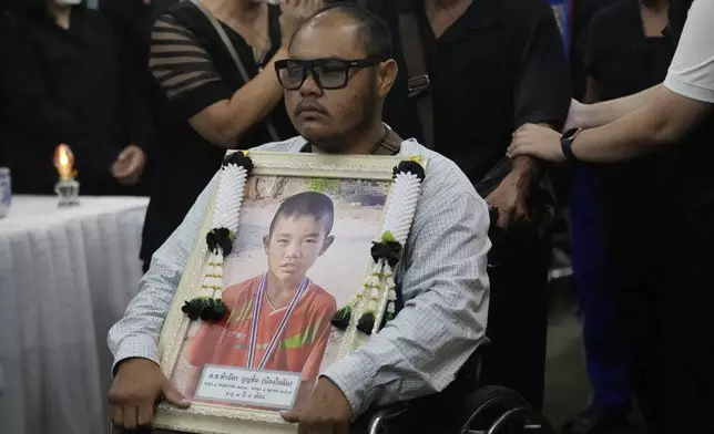 Victims' relatives carry portraits of the victims of a bus fire in a procession at Wat Khao Phraya Sangkharam School Lan Sak, Uthai Thani province, Thailand, Thursday, Oct. 3, 2024. (AP Photo/Sakchai Lalit)