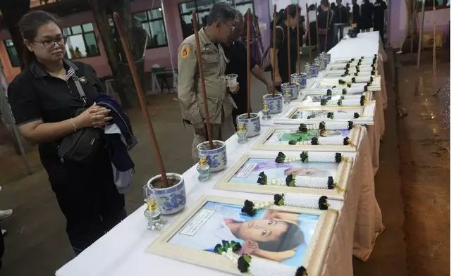 Relatives of the bus fire victims view their portraits at the Wat Khao Phraya Sangkharam School Lan Sak, Uthai Thani province, Thailand, Wednesday, Oct. 2, 2024. (AP Photo/Sakchai Lalit)