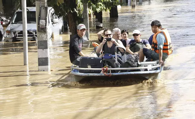 Tourists evacuate from a flood-hit area in Chiang Mai Province, Thailand, Saturday, Oct. 5, 2024. (AP Photo/Wichai Tapriew)