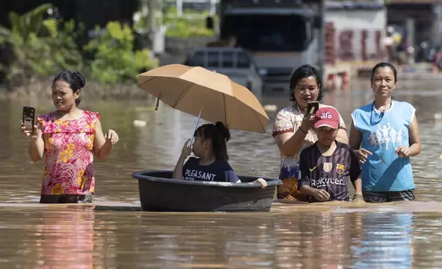 Women wade through floodwaters in Chiang Mai Province, Thailand, Sunday, Oct. 6, 2024 as the city's main river overflowed its banks following heavy seasonal rainfall. (AP Photo/Wason Wanichakorn)