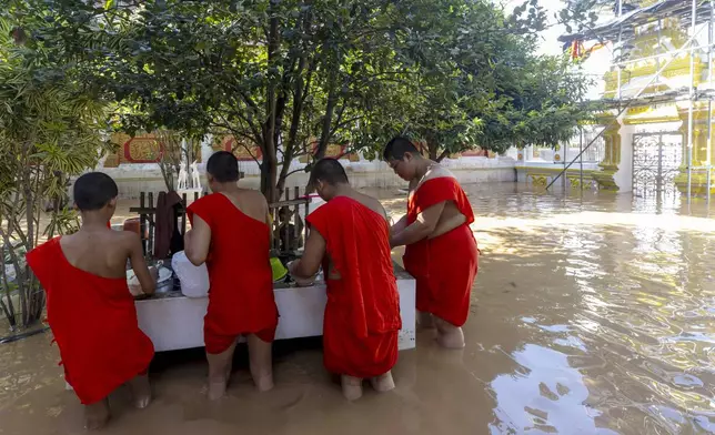 Novice clean their dish at Upagupata Temple in Chiang Mai Province, Thailand, Sunday, Oct. 6, 2024 as the city's main river overflowed its banks following heavy seasonal rainfall. (AP Photo/Wason Wanichakorn)