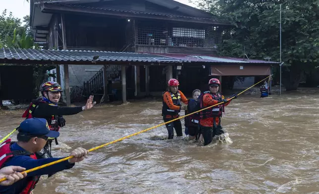 Thai rescuers help a woman from a flood-hit area in Chiang Mai Province, Thailand, Sunday, Oct. 6, 2024. (AP Photo/Wason Wanichakorn)