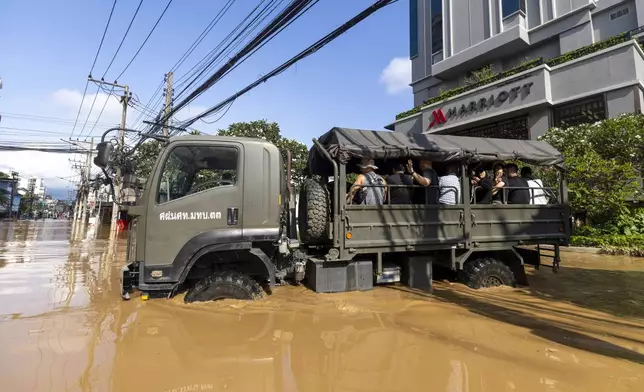 Tourists evacuate from a flood-hit area in Chiang Mai Province, Thailand, Sunday, Oct. 6, 2024 as the city's main river overflowed its banks following heavy seasonal rainfall. (AP Photo/Wason Wanichakorn)