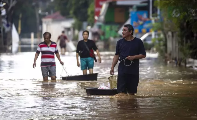 People drag their belongings through floodwaters in Chiang Mai Province, Thailand, Sunday, Oct. 6, 2024 as the city's main river overflowed its banks following heavy seasonal rainfall. (AP Photo/Wason Wanichakorn)