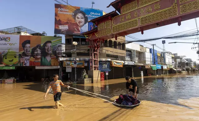 People drag their belongings through floodwaters in Chiang Mai Province, Thailand, Sunday, Oct. 6, 2024 as the city's main river overflowed its banks following heavy seasonal rainfall. (AP Photo/Wason Wanichakorn)