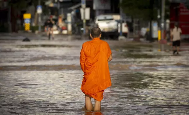 A Thai Buddhist monk wades through floodwaters in Chiang Mai Province, Thailand, Sunday, Oct. 6, 2024 as the city's main river overflowed its banks following heavy seasonal rainfall. (AP Photo/Wason Wanichakorn)