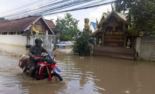 A motorcyclist wades through floodwaters in Chiang Mai Province, Thailand, Sunday, Oct. 6, 2024 as the city's main river overflowed its banks following heavy seasonal rainfall. (AP Photo/Wason Wanichakorn)