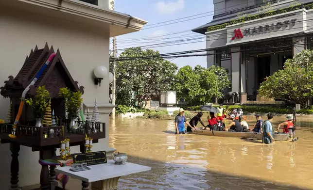 Tourists evacuate from a flood-hit area in Chiang Mai Province, Thailand, Sunday, Oct. 6, 2024 as the city's main river overflowed its banks following heavy seasonal rainfall. (AP Photo/Wason Wanichakorn)