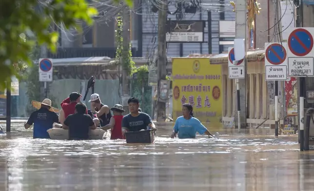 People wade through floodwaters in Chiang Mai Province, Thailand, Sunday, Oct. 6, 2024 as the city's main river overflowed its banks following heavy seasonal rainfall. (AP Photo/Wason Wanichakorn)