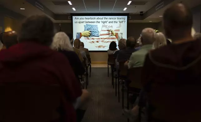 Attendees from across the political spectrum listen to a Braver Angels lecture on depolarization at the Rogers Free Library in Bristol, R.I., Thursday, Sept. 12, 2024. The non-profit organization holds workshops and mock debates across the country to help opposing political viewpoints communicate and understand each other's positions. (AP Photo/David Goldman)