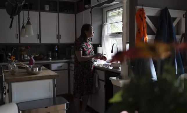 Lesley Dzik looks out her kitchen window, in Champaign, Ill., Saturday, Sept. 21, 2024. Lesley is deeply Christian. Matt, her husband sees himself as more spiritual than religious. "I get worried with Matt because I believe the Bible is truth and Matt is iffy about that," she said. "I wonder what I got myself into." (AP Photo/David Goldman)