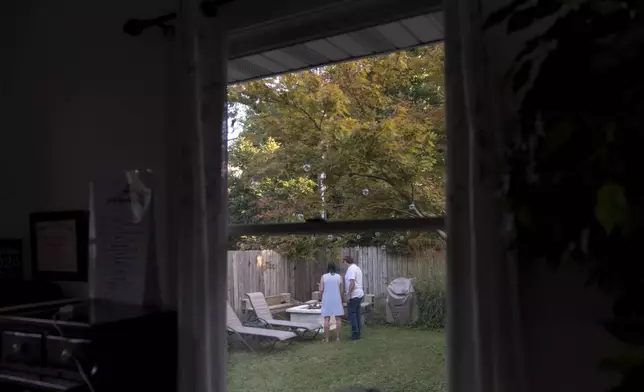 Lesley, left, and Matt Dzik, stand in their backyard in Champaign, Ill., Friday, Sept. 20, 2024. When they started dating, all it took was the sight of Democratic lawn signs outside his house ahead of the 2020 election to make her question if their relationship could work. (AP Photo/David Goldman)